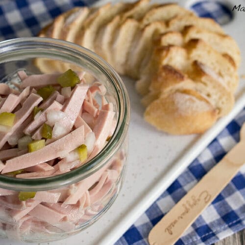 Wurstsalat ohne Käse 3 Glas Wurstsalat ohne Käse mit Wurstscheiben und Essiggurken, serviert mit Baguettescheiben.