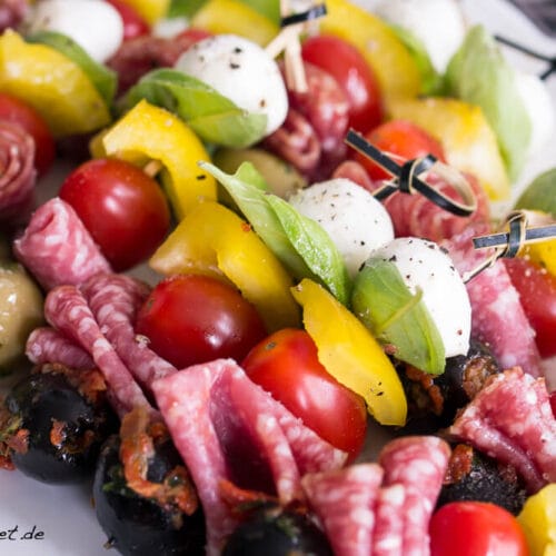 Antipasti Spieße mit Oliven, Tomaten, Mozzarella und Salami 3 Antipasti Spieße auf einem Teller mit aufgespießten Oliven, Mozzarellakugeln, Kirschtomaten und Salami.