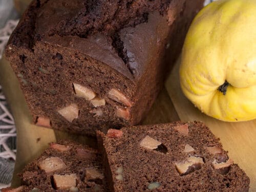 In Scheiben geschnittener Schokoladenkuchen mit Quitte auf einem Holzbrett.