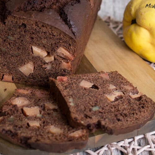 Quittenkuchen mit Schokolade und Walnuss 3 In Scheiben geschnittener Schokoladenkuchen mit Quittenstücken aus der Kastenform auf einem Holzbrett.