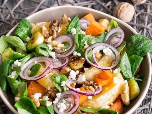 Eine Schüssel Wintersalat mit Feldsalat, gerösteten Süßkartoffeln, roten Zwiebeln, Walnüssen, Fetakäse und verschiedenen Gemüsesorten.