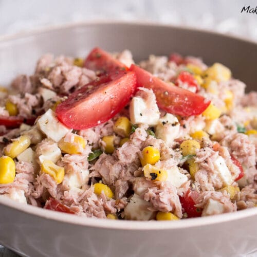 Schale mit Thunfischsalat mit Mais, Tomatenscheiben und Feta.