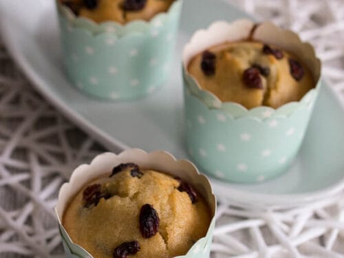 Drei Rosinenmuffins mit Apfelmus in hellblauen Tassen auf einem weißen Teller.