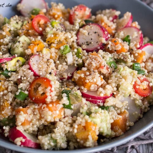 Schüssel mit Quinoa-Salat mit Avocado, Radieschen, Süßkartoffeln und frischen Kräutern.
