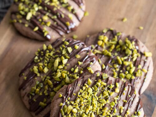 Vier Schokoladencookies mit Schokostreuseln und Pistazien.