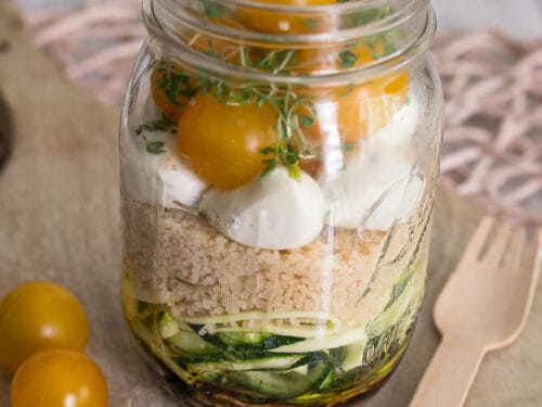 Ein Salt im Glas gefüllt mit einer Couscous, Mozzarella, Zucchini und Tomaten.