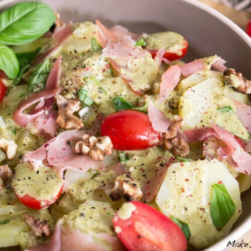 Kartoffelsalat mit Kirschtomaten, Walnüssen, Schinken, Kartoffelscheiben, Petso-Dressing und Basilikumblättern.
