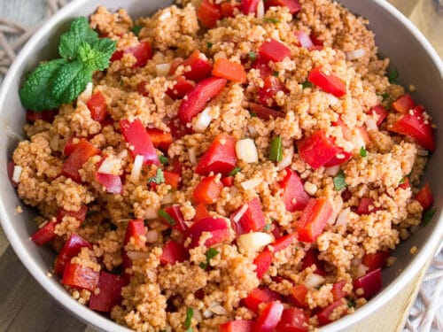 Couscous-Salat in einer Schüssel mit gewürfelten roten Paprikaschoten, Zwiebeln und Kräutern.