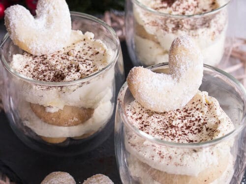 Drei Glasbecher mit Vanillekipferl-Tiramisu, jeder mit einem Vanillekipferl gekrönt.