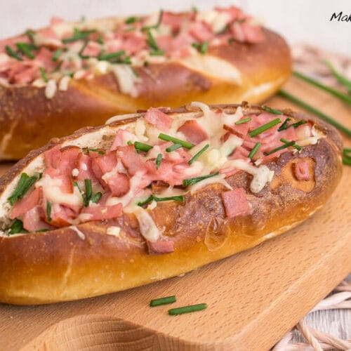 Gefüllte Laugenstangen mit Fleischkäse und Käse 3 Zwei Laugenstangen, belegt mit Fleischkäse, geschmolzenem Käse und Schnittlauch.
