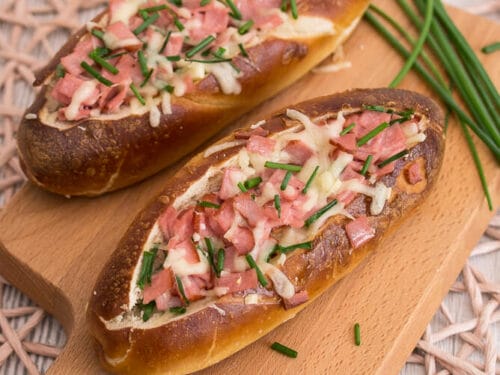 Laugenstangen mit Fleischkäse, geschmolzenem Käse und mit Schnittlauch bestreut.