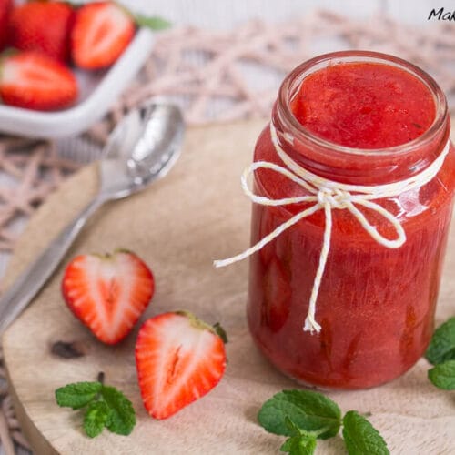 Erdbeermarmelade mit Minze 3 Erdbeermarmelade in einem Glas, frische Erdbeeren, Minzblätter und ein Löffel auf einem Holzbrett.