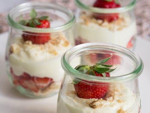 Erdbeerdesser in drei Gläsern, geschichtet mit frischen Erdbeeren und zerbröselten Keksen.