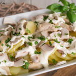 Ein weißes Gericht mit Kartoffeln, Pilzen (Champignons) und Soße.