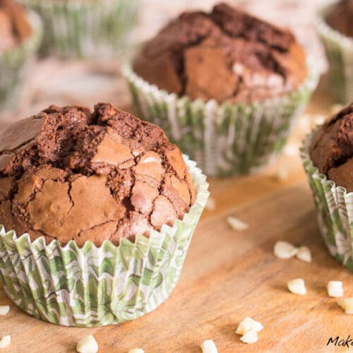 Glutenfreie Schokoladenmuffins mit gehackten Walnüssen in grün gemusterten Förmchen.