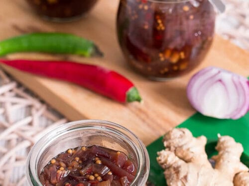 Ein Glas Zwiebelchutney mit sichtbarem Ingwer, Chilischoten und Zwiebeln; weitere Gläser mit Chutney stehen im Hintergrund.