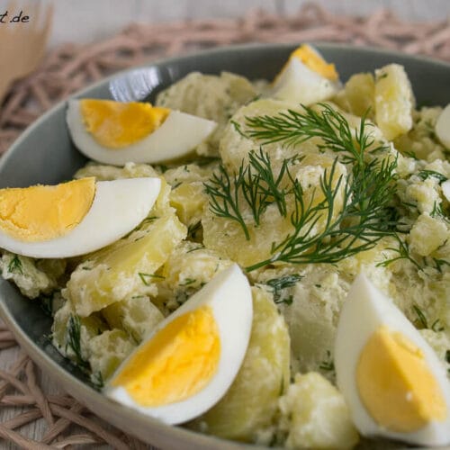 Kartoffelsalat mit Dill und in Scheiben geschnittenen hartgekochten Eiern in einer Schüssel.