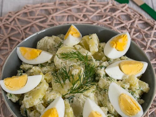 Kartoffelsalat mit in Scheiben geschnittenen hartgekochten Eiern und frischem Dill in einer Schüssel.