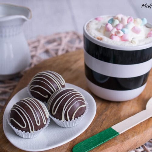 Hot Chocolate Bombs, eine Tasse heiße Schokolade mit Marshmallows und ein Löffel daneben