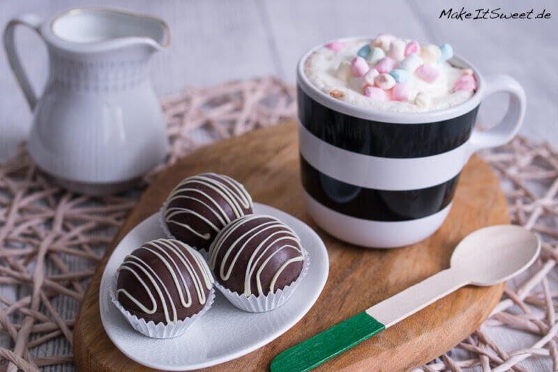 Hot Chocolate Bombs, eine Tasse heiße Schokolade mit Marshmallows und ein Löffel daneben