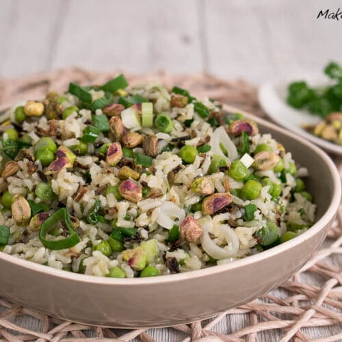 Schüssel Wildreissalat mit Pistazien mit Lauchzwiebeln, Erbsen und frischen Kräutern.