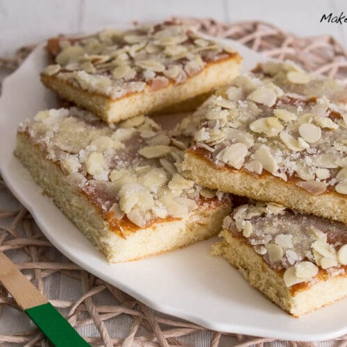 Blitz-Butterkuchen mit Mandeln 3 Mehre Stücke Blitz-Butterkuchen mit Mandelblättchen auf einem weißen Teller.