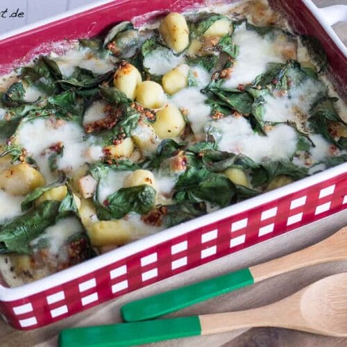 Gnocchi-Auflauf mit Hähnchen, Spinat und geschmolzenem Mozzarella in einer rot-karierten Form.