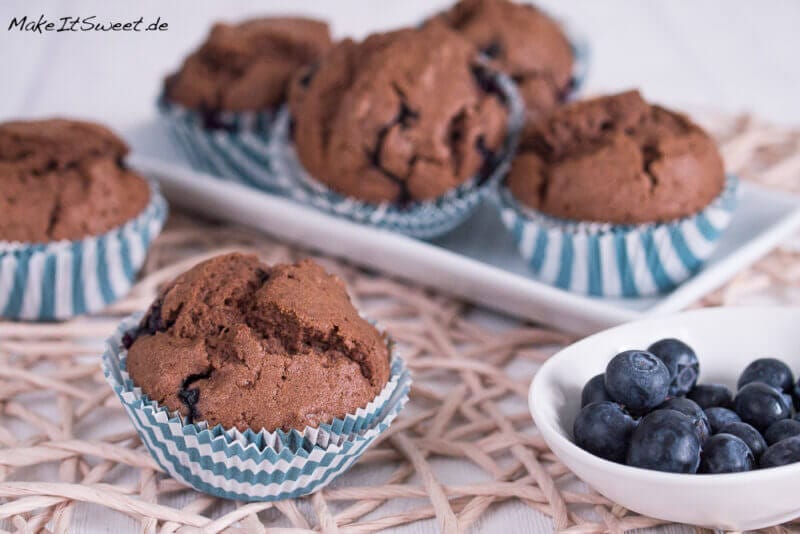 Schoko-Blaubeer-Muffins mit Blaubeeren daneben.