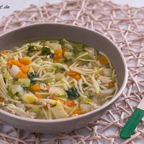 Schüssel mit Hühner-Nudel-Suppe mit Karotten, Kartoffeln und Kräutern.