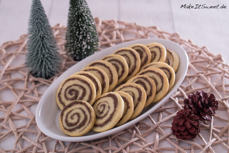 Runde Zimtschnecken Plätzchen auf einem länglichen Teller mit weihnachtlicher Doke