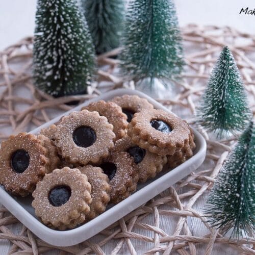 Ein mit Marmelade gefülltes und mit Puderzucker bestäubtes Linzer Tortenplätzchen.