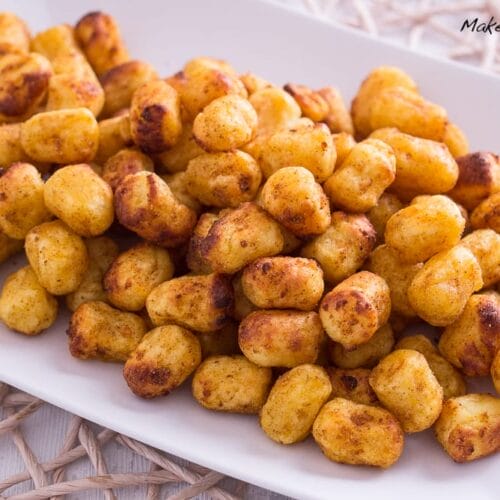 Knusprige, goldbraune Gnocchi aus der Heißluftfritteuse, die auf einem weißen Teller angerichtet sind.