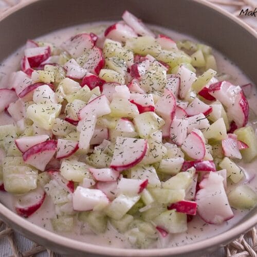 Schüssel mit cremigem Gurken- und Rettichsalat mit Joghurt, bestreut mit getrockneten Dill.