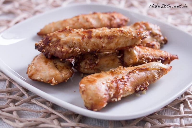 Ein Teller mit mehrere Stücken Hähncheninnenbrustfilet aus der Heißluftfritteuse, mariniert und mit Sesam