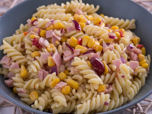 Schüssel Nudelsalat mit Schinken mit Nudeln, Mais, gehacktem Schinken, roten Zwiebeln und Kidneybohnen.