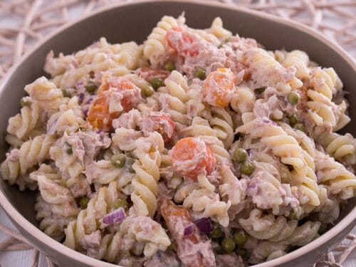 Schüssel Nudelsalat mit Thunfisch mit Nudeln, Erbsen, Möhren und roten Zwiebeln.