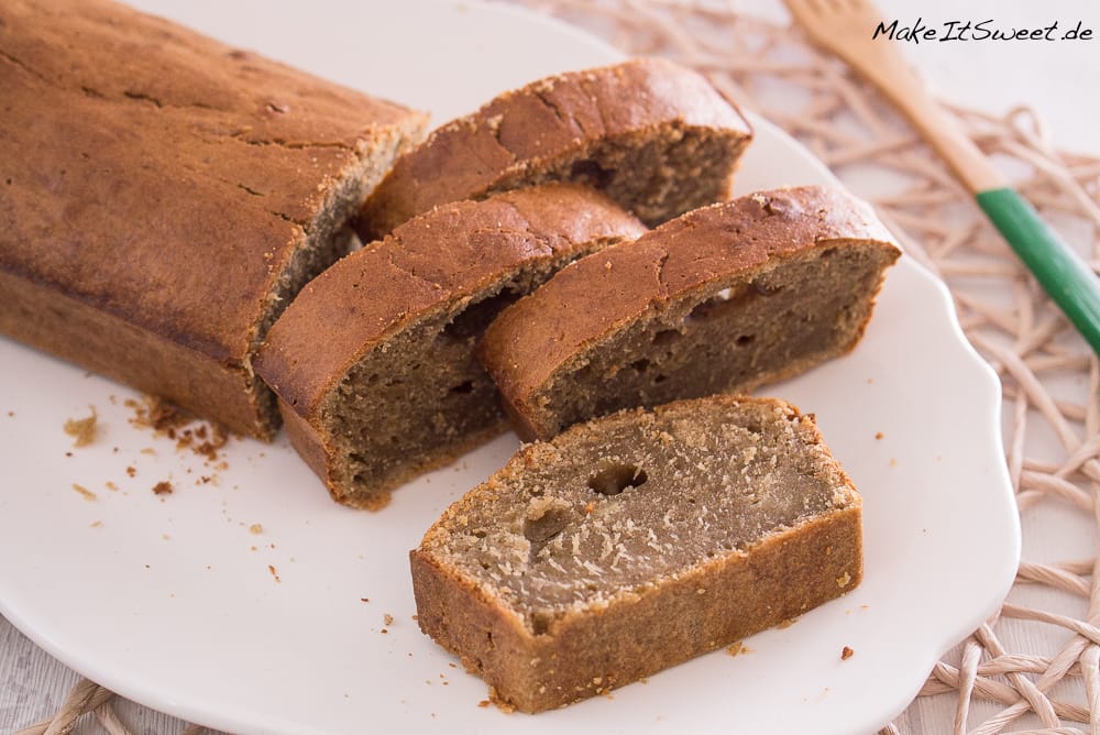 In Scheiben geschnittenes Bananenbrot mit Erdnussmus auf einem weißen Teller, der seine saftige Krume und den nussigen Belag hervorhebt.
