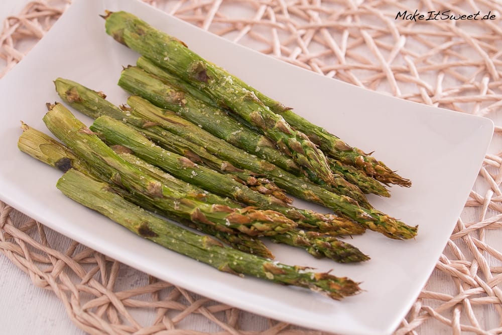 Knusprig gerösteter grüner Spargel aus der Heißluftfritteuse auf weißem rechteckigen Teller.
