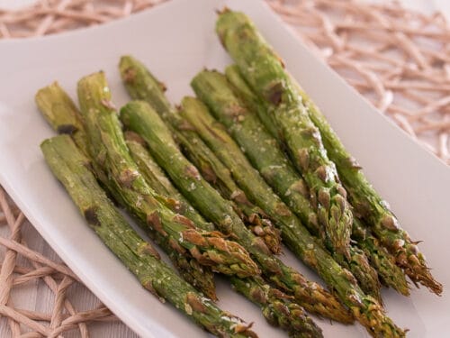 Knusprig gerösteter grüner Spargel aus der Heißluftfritteuse auf weißem rechteckigen Teller angerichtet.