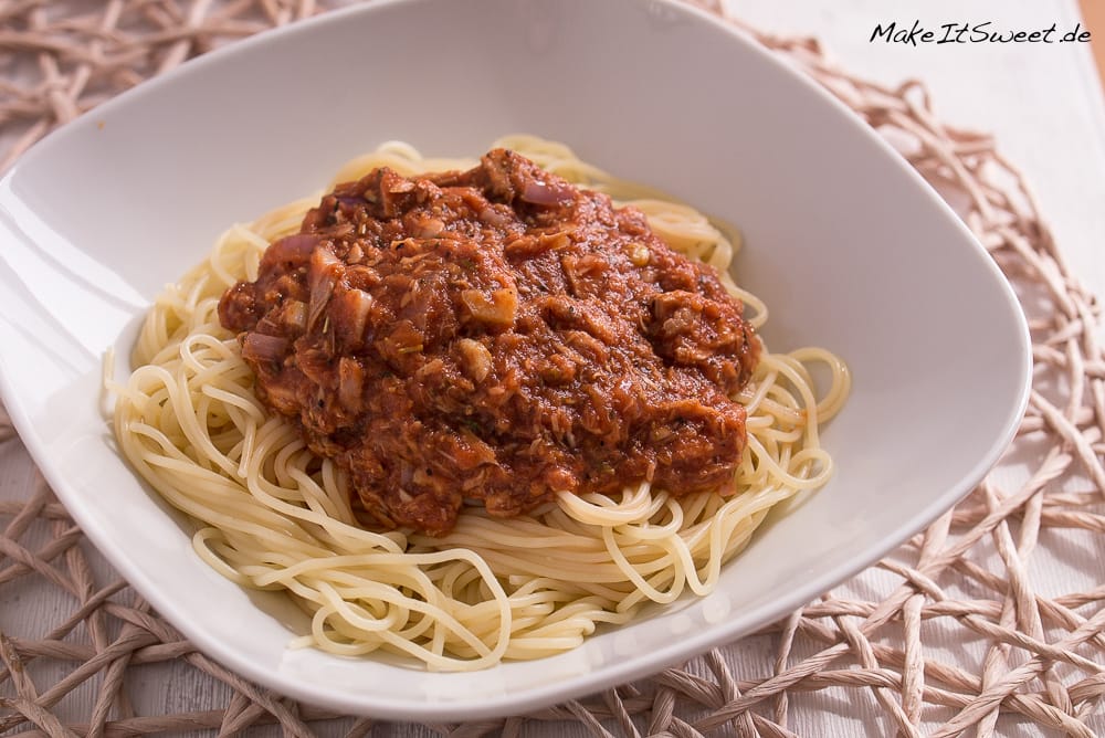 Spaghetti in einer weißen Schale, übergossen mit einer Soße aus Tomaten und Thunfisch.