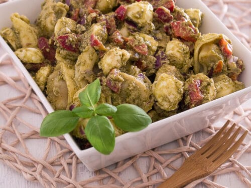 Schüssel mit Tortellini-Salat mit Pesto, Mozzarella, Paprika und frischem Basilikum.