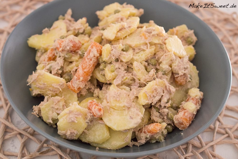 Kartoffelsalat mit Thunfisch in einer Schüssel, die sichtbare Karotten, Erbsen und Thunfisch enthält.