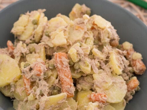 Schüssel mit cremigem Kartoffelsalat mit Thunfisch, gemischt mit Karotten und Erbsen.