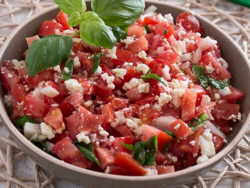 Schüssel mit Tomatensalat mit Feta und frischen Basilikumblättern.