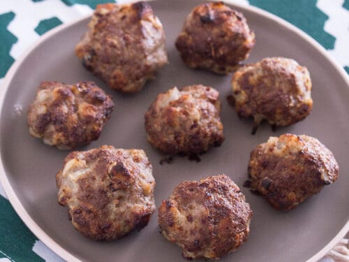 Mehrere Mini-Frikadellen aus der Heißluftfritteuse auf einem braunen Teller angeordnet.