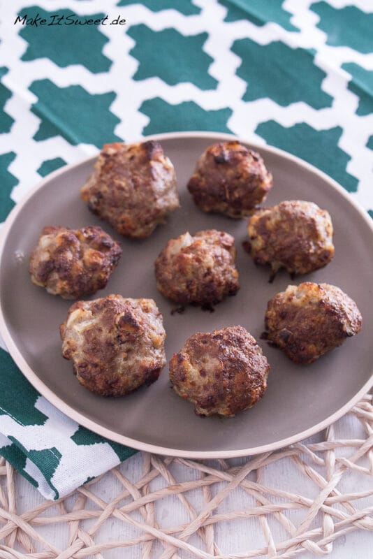 Mehrere Mini-Frikadellen aus der Heißluftfritteuse auf einem braunen Teller angeordnet.