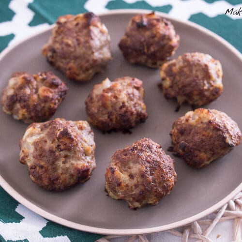 Selbstgemachte Mini-Frikadellen aus der Heißluftfritteuse mit Zwiebeln sind auf einem braunen Teller angerichtet.