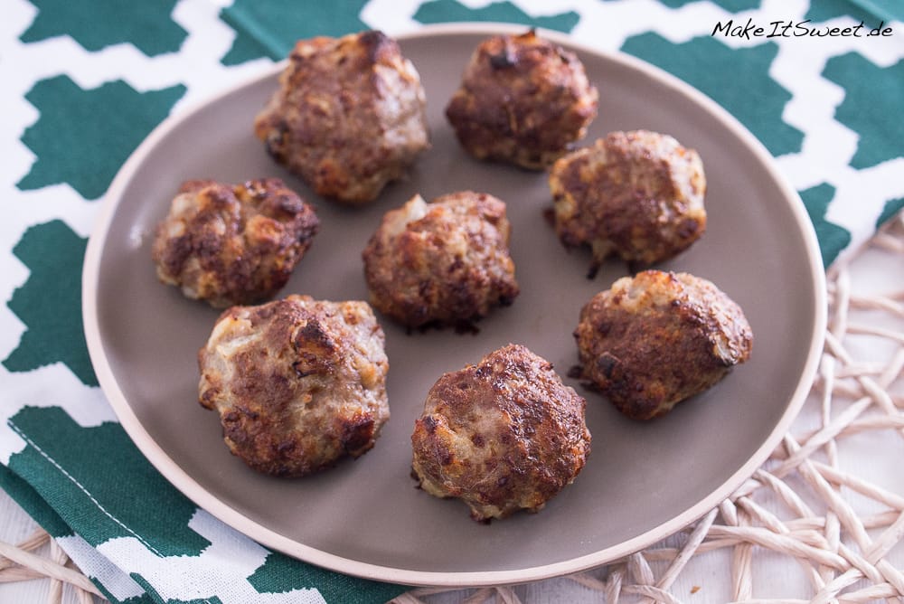 Selbstgemachte Mini-Frikadellen aus der Heißluftfritteuse mit Zwiebeln sind auf einem braunen Teller angerichtet.
