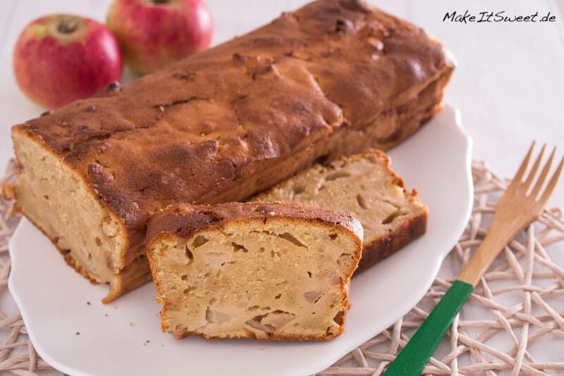 Apfel-Quark-Kuchen aus der Kastenform 1 Apfel-Quark-Kuchen aus der Kastenform auf einem weißen Teller mit Äpfeln und cremiger Quarkfüllung.