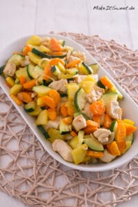 Hähnchenbrust mit Gemüse aus der Heißluftfritteuse 1 Gebratenes Hühnerfleisch, Zucchini, Karotten und Kartoffeln auf einem weißen Teller.